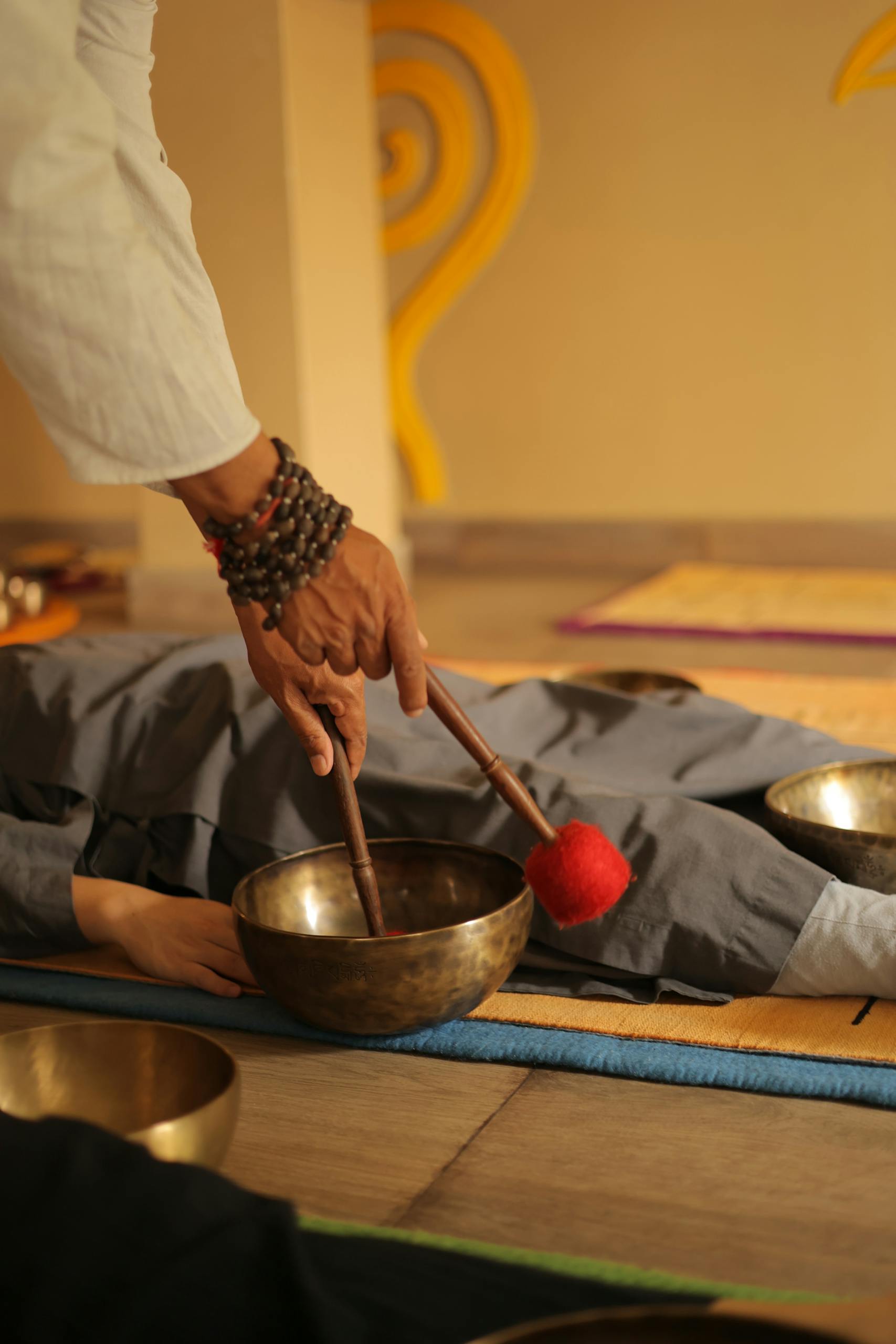 A tranquil scene of sound healing therapy using singing bowls on a relaxed participant.