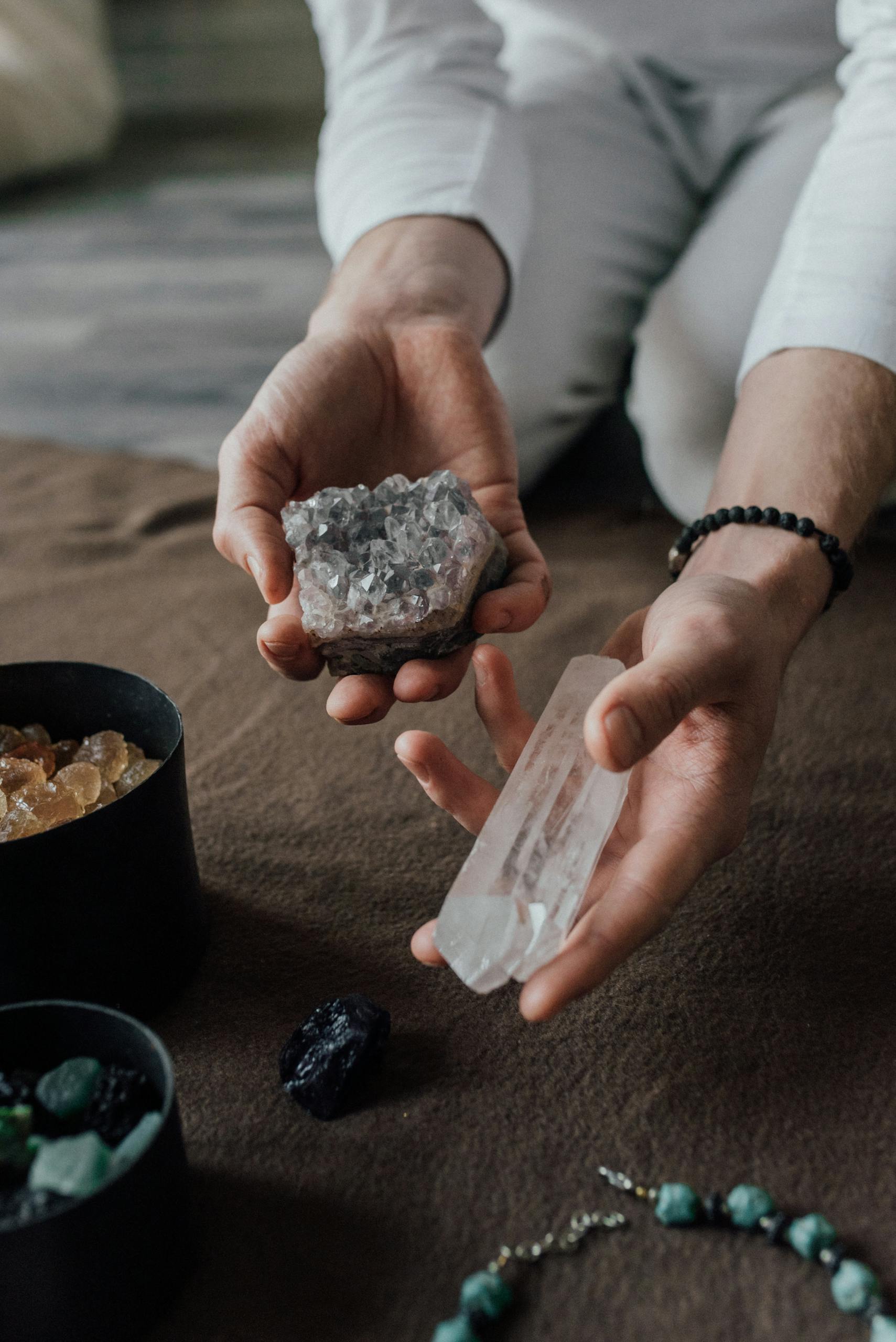 Hands holding healing crystals, including quartz and amethyst, for natural spiritual practice.