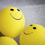Three yellow smiley face balloons creating a cheerful and bright atmosphere indoors.